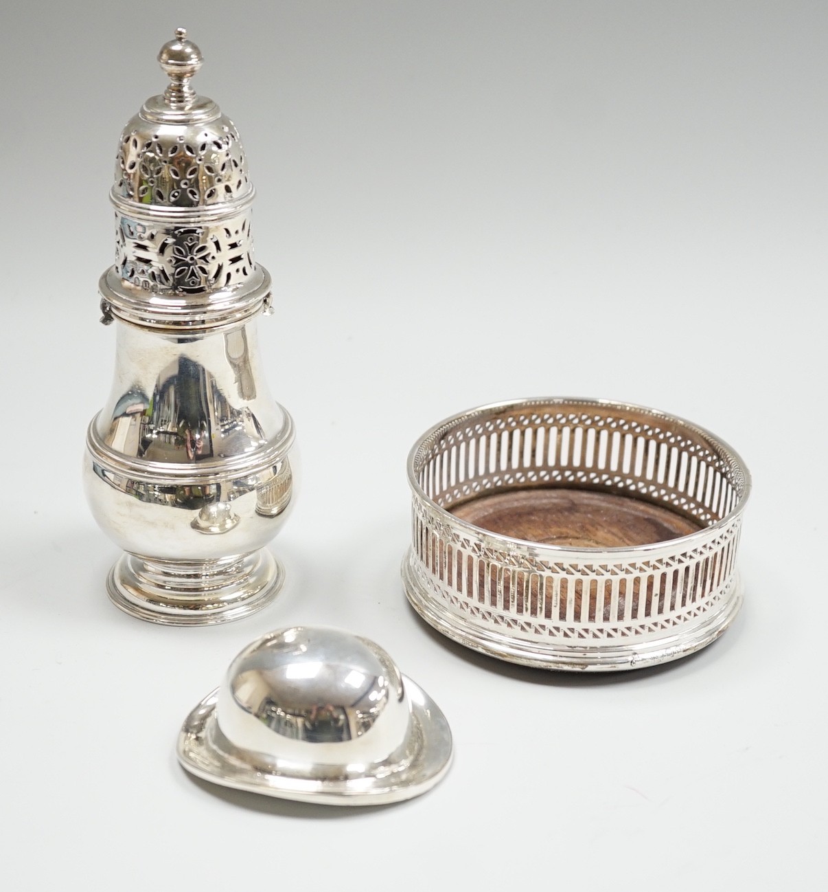 A George V Brittania standard silver baluster sugar caster, Daniel & John Welby, London, 1915, 15.7cm, a modern silver mounted wine coaster and a plate novelty bowler hat dish.